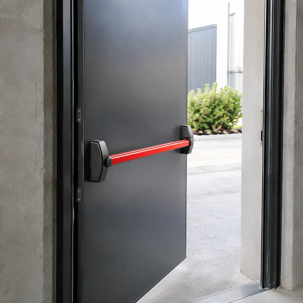 Barre anti-panique rouge sur une porte de secours métallique d'un bâtiment professionnel